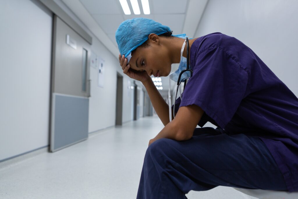 Tensed surgeon with hand on forehead sitting in corridor of the hospital